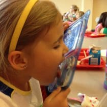 Child licking yogurt off of lid