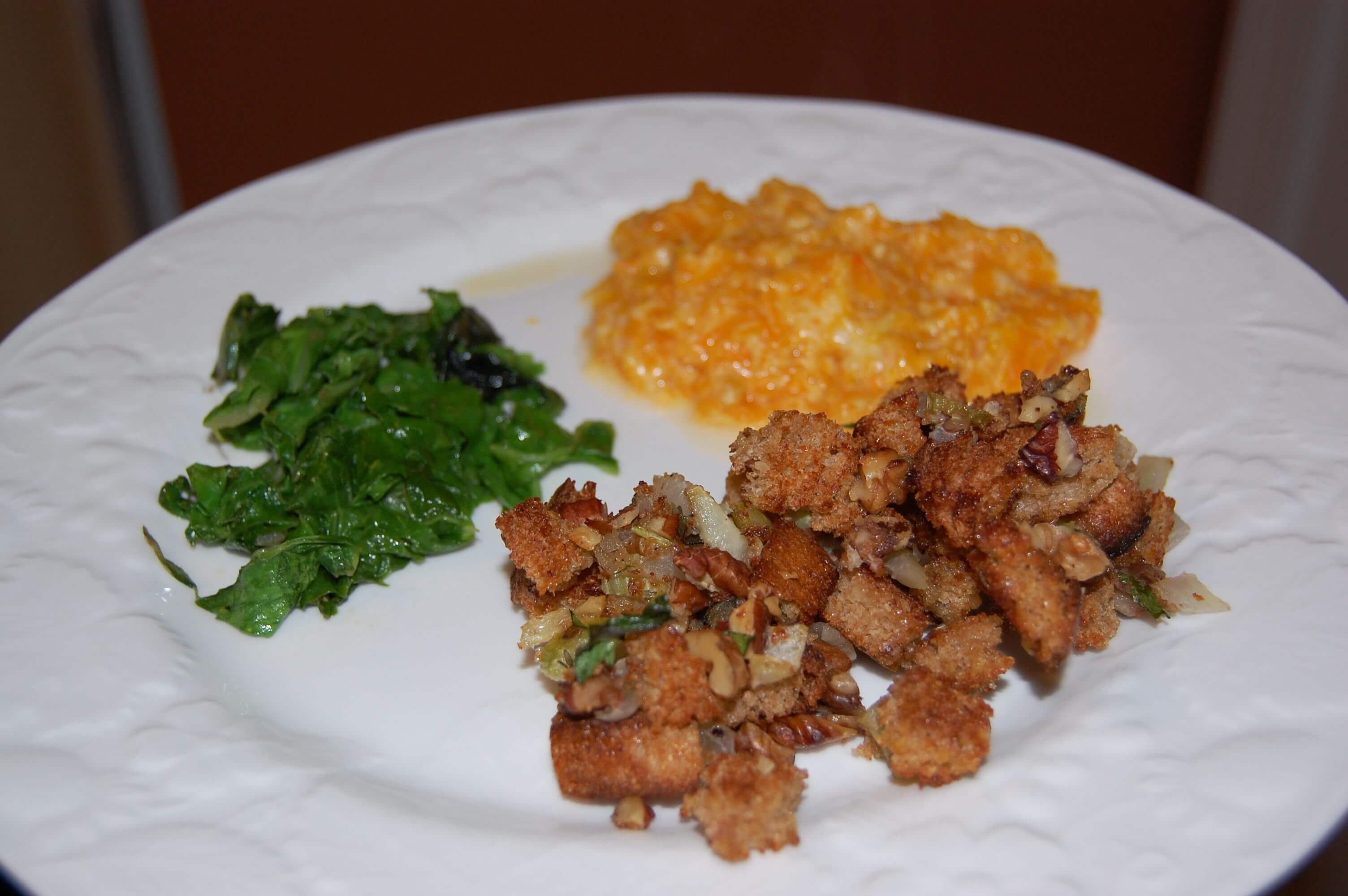 A plate of bread/nut stuffing, butternut squash gratin and some fresh greens. 